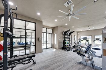 Spacious fitness center with exercise equipment and ceiling fan
